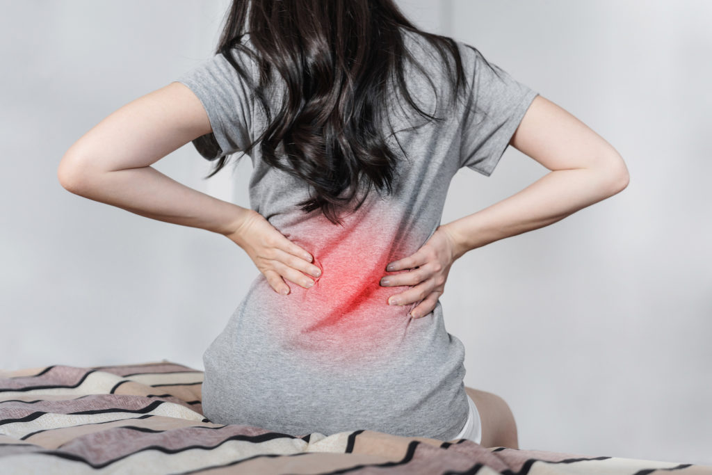 woman sitting in a bed suffer from back pain