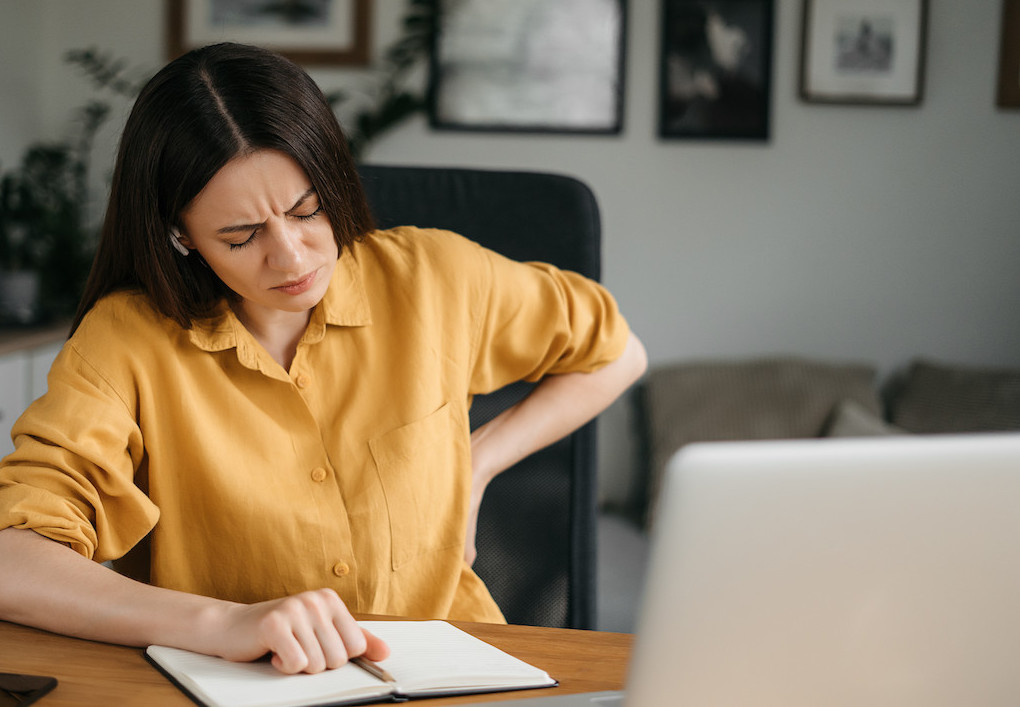 woman in office felt pain in lower back due to poor posture in sitting